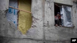 Một thường dân bên trong một khu nhà bị trúng pháo hôm thứ Bảy ở Mariupol, Ukraine, 28/1/2015.