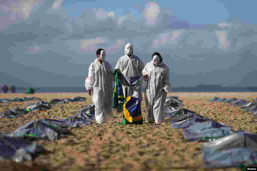 Activists from NGO Rio de Paz carry a Brazilian flag as they display hundreds of plastic bags, representing dead bodies, during a protest against Jair Bolsonaro&#39;s COVID-19 policies, in Copacabana beach, in Rio de Janeiro, Brazil.