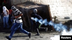 Palestinian youths run from tear gas canisters fired by Israeli border police during clashes at a checkpoint between the Shuafat refugee camp and Jerusalem, Nov. 7, 2014. 