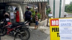 Masyarakat miskin yang membutuhkan makan siang diperbolehkan mengambil nasi bungkus dan vitamin C yang telah disediakan. (Foto: VOA/Petrus Riski)