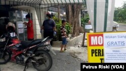 Masyarakat miskin yang membutuhkan makan siang diperbolehkan mengambil nasi bungkus dan vitamin C yang telah disediakan. (Foto: VOA/Petrus Riski)