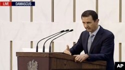 ປະທານາທິບໍດີ ຊີ​ເຣຍ Bashar Assad ​ກ່າ​ວຄຳ​ປາ​ໄສ​ໃນນະຄອນຫຼວງ Damascus, ປະ​ເທດ ຊີ​ເຣຍ. ພາບ​ນີ້​ແມ່ນໄດ້​ມາ​ຈາກ​ວິ​ດີ​ໂອ ອອກ​ອາກາດ​ໂດຍ​ໂທລະ​ພາບ ລັດຖະບານ ອິຣ່ານ​ ຊ່ອງ​ພາສາ​ອັງ​ກິດ. ກໍ​ລະ​ກົດ 26, 2015. 