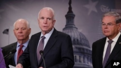 Ketua Komite Militer Senat AS, Senator John McCain (tengah), didampingi oleh Senator Ben Cardin (kiri) dan Senator Bob Menendez, berbicara dalam konferensi pers di Capitol Hill (10/1). (AP/J. Scott Applewhite)