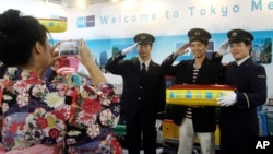 FILE - A Taiwanese visitor poses with uniformed employees of Tokyo Metro Co. for a souvenir photo at the booth of the Tokyo subway company at the Taipei International Travel Fair in Taipei, Taiwan, Nov. 8, 2014. (AP Photo/Chiang Ying-ying) 