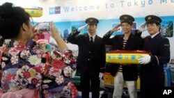 FILE - A Taiwanese visitor poses with uniformed employees of Tokyo Metro Co. for a souvenir photo at the booth of the Tokyo subway company at the Taipei International Travel Fair in Taipei, Taiwan, Nov. 8, 2014. Taiwanese can travel visa-free to 166 countries.