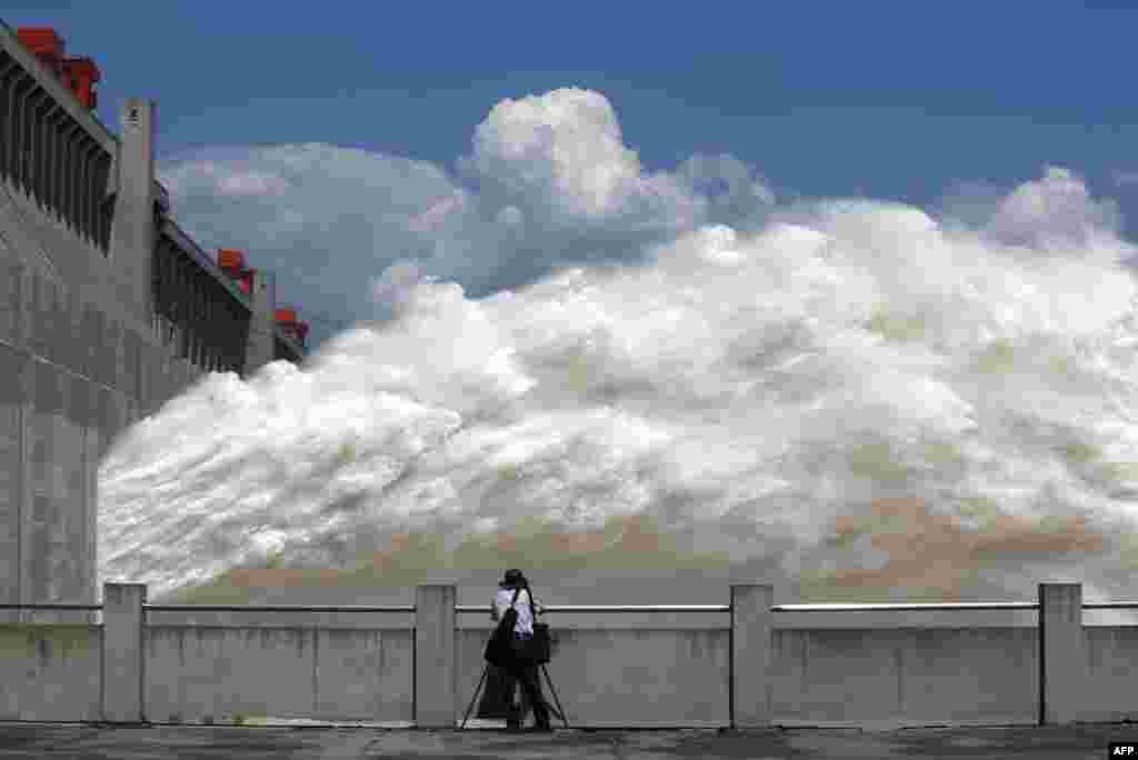 A man takes pictures of floodwater released from the Three Gorges Dam, a giant hydropower project on the Yangtze River, in China's Hubei province. The heavy downpours raised water in the dam to the highest level of the year.