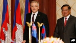 Australian Immigration Minister Scot Morrison, left, walks is accompanied by Cambodian Interior Minister Sar Kheng, right, as they arriving for a signing ceremony of a controversial deal on resettlement of refugees inside the Interior Ministry, in Phnom P