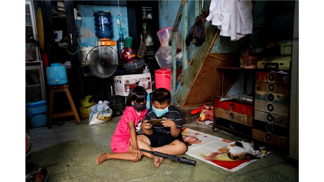 Anak-anak mengenakan masker sambil memainkan ponsel di dalam sebuah rumah di kawasan padat penduduk di Jakarta. (Foto: ilustrasi/Reuters)