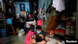 Anak-anak mengenakan masker sambil memainkan ponsel di dalam sebuah rumah di kawasan padat penduduk di Jakarta saat pandemi virus corona (Covid-19), 1 April 2020, sebagai ilustrasi. (Foto: Reuters)