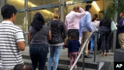 FILE - People line up outside the building that houses the immigration courts in Los Angeles, June 28, 2018.