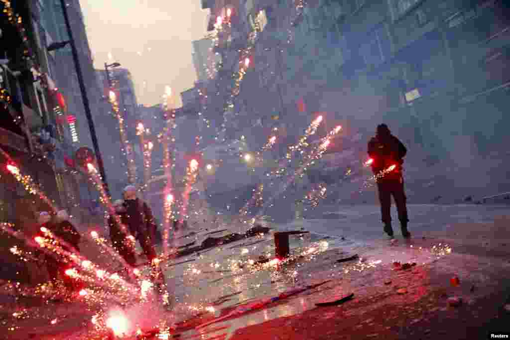 Fireworks thrown by anti-government protesters explode behind riot police near Taksim square in Istanbul. The protest is triggered by the death of a teenager who was wounded in street clashes last summer.