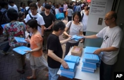 People queue up to receive the copy of the Hong Kong Chief Executive Carrie Lam's first policy address at a street in Hong Kong, Oct. 11, 2017.