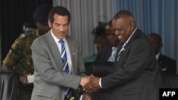 FILE - Botswana's Former President Seretse Ian Khama (L) shakes hands with his vice-president, now current President, Mokgweetsi Masisi during a rally in his village Serowe on March 27, 2018, before officially stepping down on March 31