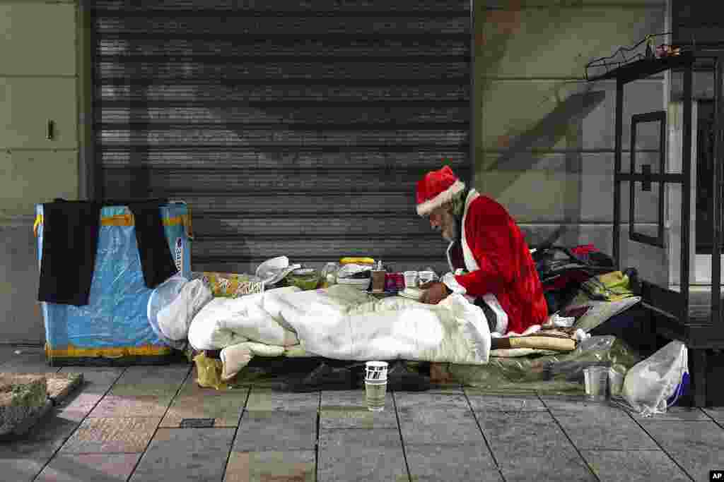 A homeless man, name given Rafael, wears a Santa Claus outfit as he prepares to have dinner by the side of a road, in Milan, Italy.