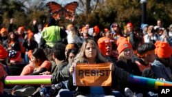 A woman holds up a sign that says, "resist," as supporters of the Deferred Action for Childhood Arrivals (DACA) block an intersection near the U.S. Capitol in support of DACA recipients, March 5, 2018, on Capitol Hill in Washington. 