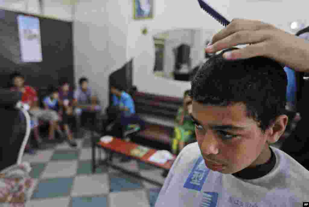 A Palestinian boy, Muhammed Hasouna, 14, has his hair cut at a barber shop in preparation for Eid, in Jebaliya refugee camp, northern Gaza Strip, July 27, 2014.