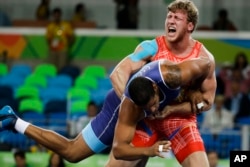 Armenia's Artur Aleksanyan, red, competes against Cuba's Yasmany Daniel Lugo Cabrera for the gold medal during the men's wrestling Greco-Roman 98-kg competition at the 2016 Summer Olympics in Rio de Janeiro, Brazil, Aug. 16, 2016.