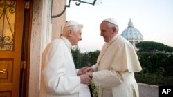 Pope Emeritus Benedict XVI, left, welcomes Pope Francis as they exchange Christmas greetings, at the Vatican, Dec. 23, 2013. 