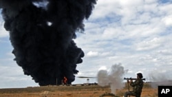 A rebel fighter fires a rocket-propelled grenade in front of a gas storage terminal during a battle on the road between Ras Lanuf and Bin Jiwad, Mar 9 2011