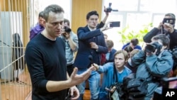 Russian opposition leader Alexei Navalny, foreground, speaks to press in a court room in Moscow, Russia, March 27, 2017. 