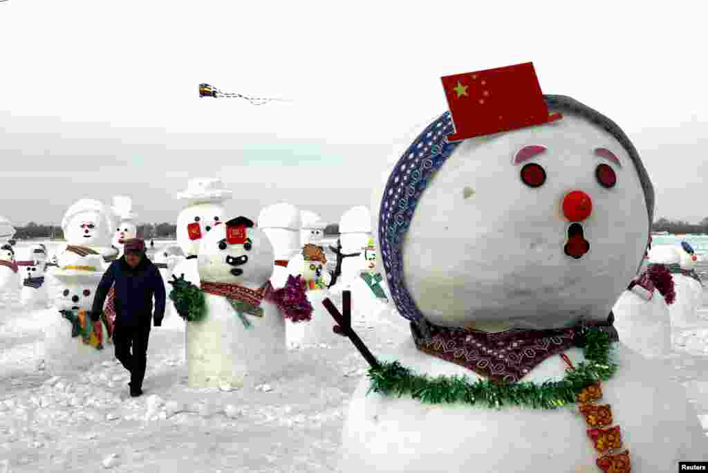 A man walks between snowmen on Songhua River that displays 2019 snowmen as a part of yearly ice festival, in the northern city of Harbin, Heilongjiang province, China.