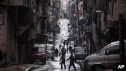 Warga Suriah berjalan melewati bangunan-bangunan yang rusak berat akibat bentrokan Tentara Pemberontak Suriah dan tentara pemerintah di Aleppo (4/12). Kelompok HAM melaporkan bahwa pasukan pemerintah telah menembakkan roket ke kawasan Daraya dan Moadamiah yang dikuasai pemberontak di sebelah barat daya ibukota, Jum'at (7/12).