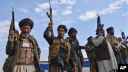 FILE - Afghan militia men raise their weapons as they stand guard in the Achin district of Nangarhar province east of Kabul, Afghanistan, Dec. 27, 2015. 