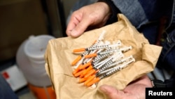 FILE - A woman shows clean syringes at a needle exchange outreach center in New York. The stigmatization of drug users in rural areas of the United States is seen as having contributed to a rise in deaths among white women.