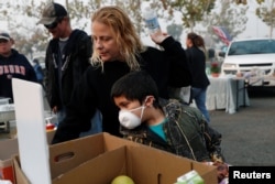 After losing their home in Magalia in the Camp Fire, Robin Tompkins and her son, Lukas, line up for a free meal in a makeshift evacuation center in Chico, Calif., Nov. 16, 2018.