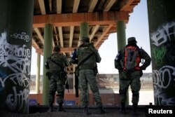 Miembros de la Guardia Nacional de México se ubican bajo el puente internacional Paso del Norte que conecta a EE.UU. y México, como parte de una operación en curso para evitar que los migrantes crucen ilegalmente a los Estados Unidos, en Ciudad Juárez, México. Junio 25, de 2019.