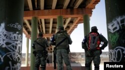 Miembros de la Guardia Nacional de México se ubican bajo el puente Internacional Paso del Norte que conecta Estados Unidos con México, como parte de una operación para evitar que los migrantes crucen ilegalmente a Estados Unidos, en Ciudad Juárez, México, 24 de junio de 2019. 
