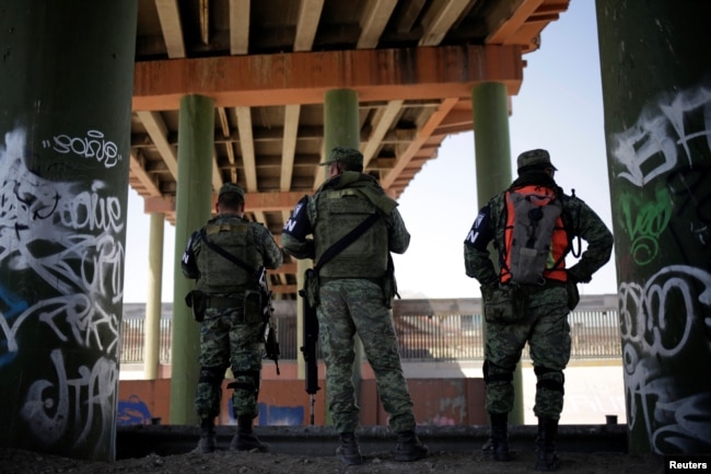 Miembros de la Guardia Nacional de México se ubican bajo el puente internacional Paso del Norte que conecta a EE.UU. y México, como parte de una operación en curso para evitar que los migrantes crucen ilegalmente a los Estados Unidos, en Ciudad Juárez, México. Junio 25, de 2019.