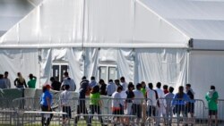 FILE - Children line up to enter a tent at a shelter for migrant children in Homestead, Florida, Feb. 19, 2019. President Joe Biden says he supports compensation for migrant families whose children where separated from them at the U.S.-Mexico boder.