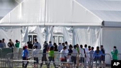 FILE - Children line up to enter a tent at a shelter for migrant children in Homestead, Florida, Feb. 19, 2019. President Joe Biden says he supports compensation for migrant families whose children where separated from them at the U.S.-Mexico boder.