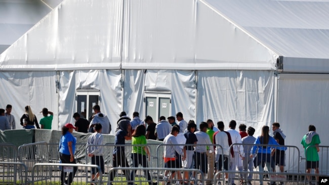 FILE - Children line up to enter a tent at a shelter for migrant children in Homestead, Florida, Feb. 19, 2019. President Joe Biden says he supports compensation for migrant families whose children where separated from them at the U.S.-Mexico boder.