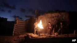 Keluarga Palestina menghangatkan diri dengan membuat perapian saat listrik mati di kawasan permukiman miskin di Khan Younis, Jalur Gaza selatan (foto: dok).