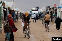 FILE - Syrian refugees ride bicycles during rainy weather at the Zaatari refugee camp in the Jordanian city of Mafraq, near the border with Syria, Dec. 18, 2016.