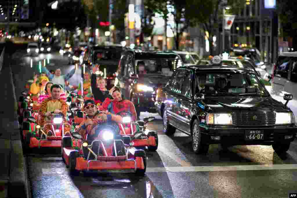 A group of sightseers in go-karts wait at a red light in the Omotesando district of Tokyo. A guide leads the group dressed as cartoon characters in go-karts through the city visiting landmarks along the way.