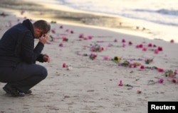 A man reacts near scattered flowers during a vigil for Justine Damond, who was shot by a Minneapolis police officer over the weekend, at Sydney's Freshwater Beach in Australia, July 19, 2017.