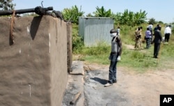 FILE - A man collecting bodies to bury in a mass grave approaches a burned hut containing charred corpses, on the outskirts of Yei, a center of the country's renewed civil war, southern South Sudan, Nov. 15, 2016.