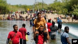 아이티 이주민들이 18일 멕시코 국경에서 강을 건너 미국 남부 델 리오 쪽으로 들어오고 있다. 
