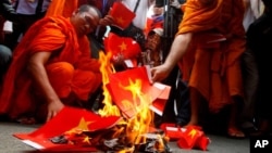 Cambodian protesters burn mock Vietnamese flags during a protest at a blocked main street in front of Vietnamese Embassy in Phnom Penh, Cambodia, Wednesday, Oct. 8, 2014. 