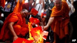 Cambodian protesters burn mock Vietnamese flags during a protest at a blocked main street in Cambodian protesters burn mock Vietnamese flags during a protest at a blocked main street in front of Vietnamese Embassy in Phnom Penh, Cambodia, Wednesday, Oct. 8, 2014. The protesters on Wednesday demanded the Vietnamese government to apologize for comments four months ago they made stating the territory of southern Vietnam (Mekong Delta) was owned by Vietnam long ago. The southern Vietnam was part of Cambodia and handed over to Vietnam by France in June 4, 1949 during the France colonial era. (AP Photo/Heng Sinith)