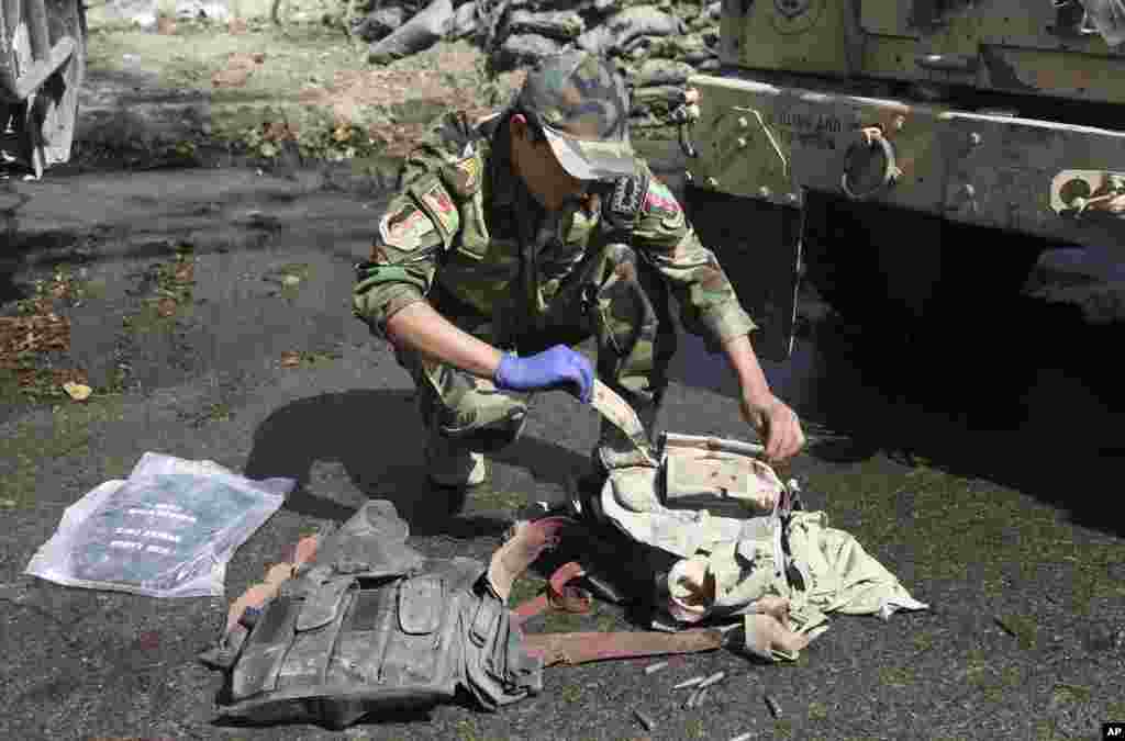 An Afghan army soldier inspects bullet proof vests found after Taliban insurgents staged a multi-pronged attack on a police station in Jalalabad, eastern Afghanistan, March 20, 2014. 