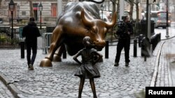 A camera man films a statue of a girl facing the Wall St. Bull, as part of a campaign by US fund manager State Street to push companies to put women on their boards, in the financial district in New York, March 7, 2017.