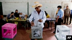 Seorang warga di Catacamas, Honduras, memberikan suaranya dalam pemilihan umum (24/11). (AP/Eduardo Verdugo)