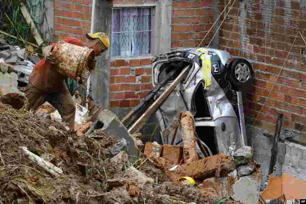 A volunteer searches for people in the damage after heavy rain caused a landslide in Franco da Rocha, Sao Paulo state, Brazil.