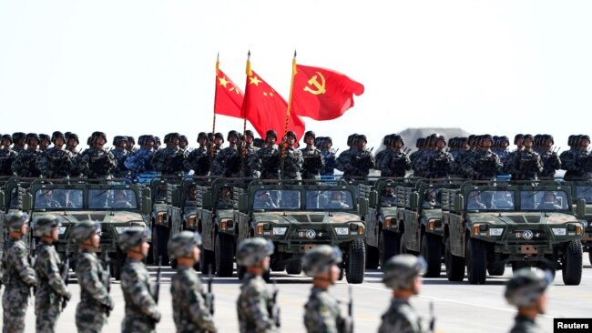 中国解放军军人在内蒙古朱日和训练基地参加阅兵，庆祝解放军建军90周年。中共党旗在前，国旗居中，军旗在后（2017年7月30日）