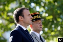 FILE - French President Emmanuel Macron, left, and Chief of the Defense Staff Gen. Pierre de Villiers, right, drive down the Champs Elysees avenue during Bastille Day parade in Paris, July 14, 2017.