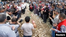 People mourn at the grave of a dead miner after the burial service in a cemetery in Soma, a district in Turkey's western province of Manisa May 15, 2014. Loudspeakers broadcast the names of the dead and excavators dug mass graves in this close-knit Turkis